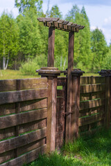 Wooden garden fence with closed door and green grass on a spring day