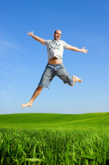 Fototapeta na wymiar Man making a big jump on a beautiful green meadow
