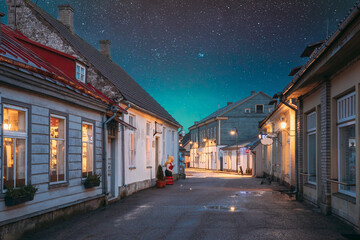 Kuressaare, Estonia. Houses At Kauba Street In Evening Or Night Illuminations. Old Traditional Houses On Narrow Street. Amazing Bold Bright Blue Starry Sky Gradient Above Houses. Azure Sky Background.