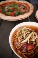 pho broth, Vietnamese soup in a deep plate with meat, wooden Chinese sticks and two quail eggs on a dark background