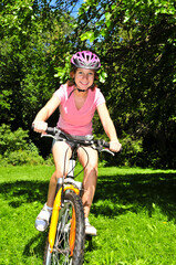 Obraz premium Portrait of a teenage girl riding a bicycle in summer park outdoors