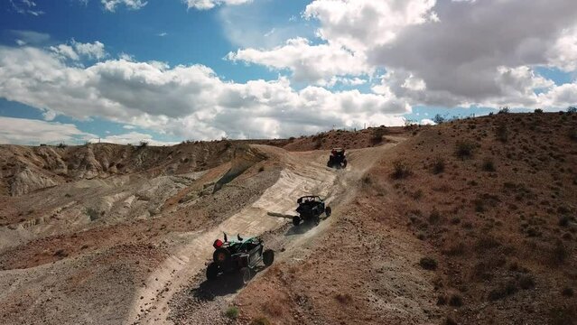 UTVs driving up a dirt desert trail
