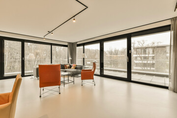 a living room with two orange chairs and a large window looking out onto the street in front of the house