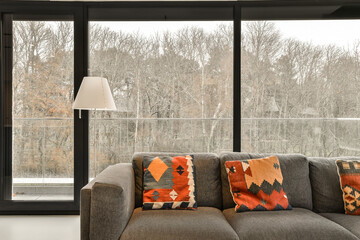 a living room with a couch and large window looking out onto the trees outside in the winter seasoning area