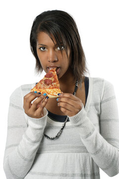 An attractive female eating a slice of pepperoni pizza.