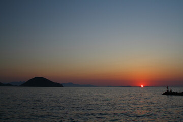 Tourists on holiday in the famous resort town of Bodrum spend time fishing at sunset.