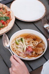 pho broth, Vietnamese soup in a deep plate with meat, wooden Chinese sticks and two quail eggs on a dark background