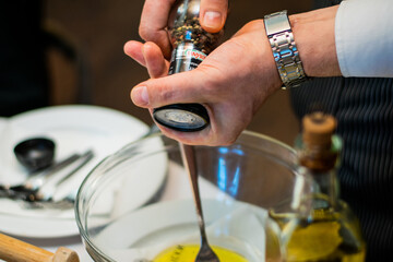 Restaurant waiter serving elaborate  - Beef tartare served on wooden board with various garnishes and egg yolk and person eats it