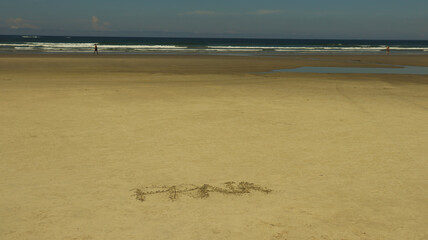 Palavra Praia escrito na areia da praia de rivieira de são lourenço em bertioga SP Brasil. 