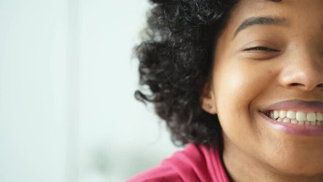 Beautiful african american happy girl with afro hairstyle smiling. Young woman eye half face portrait close up. Young african woman with curly hair laughing. Natural beauty happy people concept