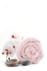 Obraz na płótnie Canvas Pink rolled up towel with massage stones on white background