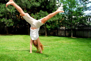 Young girl doing a cartwheel on green grass