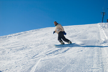 Naklejka na ściany i meble Man snowboarder on a mountain, blue sky in background stock photo