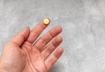 woman hand with many pills tablets in palm,different color and shape,capsules.one pill on girl female finger.medicine treatment concept, antibiotics,vitamins.gray tiles back.stack plastic blisters