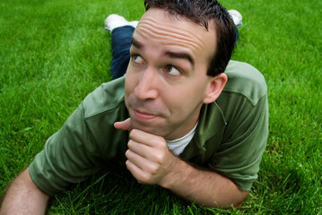 A young man lying in the grass, thinking about something