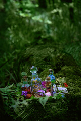 Magic witch bottles and mineral gemstones in forest, green natural background. Witchcraft, Magic...