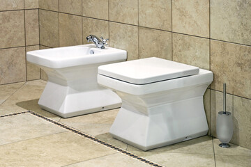 White bidet and toilet in beige lavatory