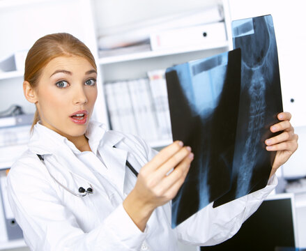 Portrait of confused female doctor examining x-ray picture