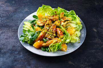 Traditioneller deutscher Eisberg und Feldsalat serviert mit Hähnchen, Avocado und Orangenscheiben mit pikanter süß saurer Currysauce serviert als Nahaufnahme auf einem Designteller mit Textfeld 