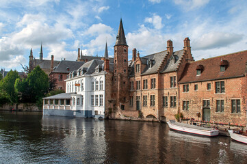 Bruges, Belgium - Old brick houses in the city center built over a canal with boats