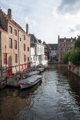 Bruges, Belgium - Old brick houses in the city center built over a canal with boats