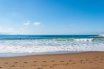 Big Waves crashing creating white foam that vaporises in the air. Sopelana beach near Bilbao. Surfers waiting for the perfect wave. Day of relaxation and tranquility with Footprints on the sand.