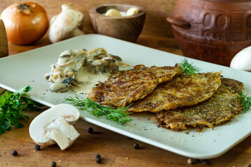 potato pancakes with mushrooms and cream sauce on a wooden table.