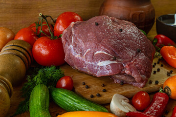 Raw beef steak with vegetables and spices on a rustic wooden background