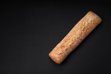 Crispy wheat flour baguette with sesame seeds on a wooden cutting board