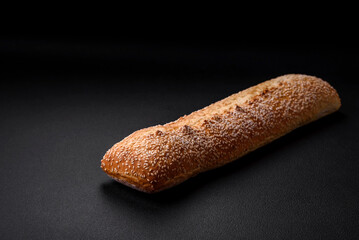 Crispy wheat flour baguette with sesame seeds on a wooden cutting board