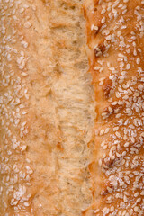 Crispy wheat flour baguette with sesame seeds on a wooden cutting board