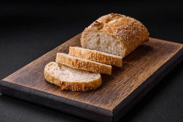 Crispy wheat flour baguette with sesame seeds on a wooden cutting board