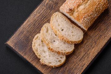 Crispy wheat flour baguette with sesame seeds on a wooden cutting board
