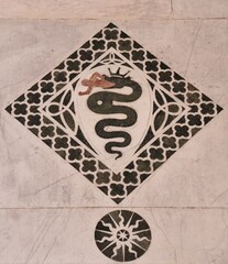 Serpente che mangia un uomo, in un quadrato decorativo mosaico di marmo, su dei Santi Giovanni e Reparata del Duomo di Lucca, Toscana, Italia
