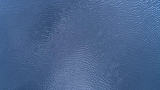 Blue river water surface with ripples and light reflection. Texture of clean freshwater of Nissan river.