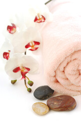 Obraz na płótnie Canvas Pink rolled up towel with massage stones on white background