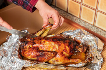 Close-up of woman cutting roast turkey with knife. Festive food.