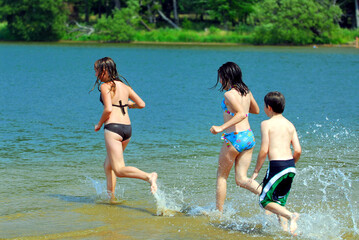 Group of young children running into water at the beach