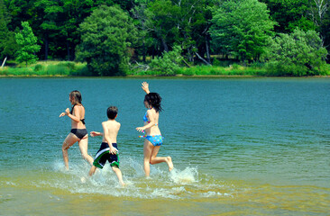 Group of young children running into water at the beach