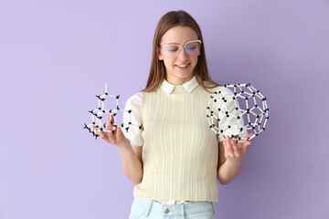 Female student with molecular models on lilac background