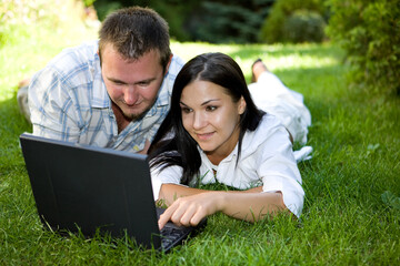 couple lying on grass with laptop