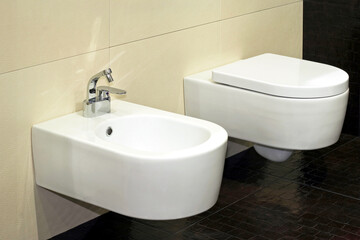 White bidet and toilet in brown lavatory