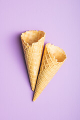 Empty wafer cone. Sweet ice cream cornet on violet background. Top view.