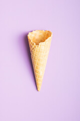 Empty wafer cone. Sweet ice cream cornet on violet background. Top view.