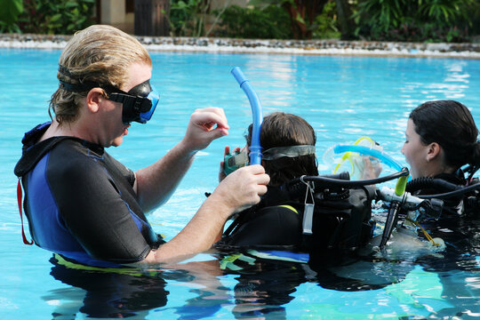 Scuba diving instructor demonstates a skill to a student in a swimming pool.