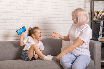 Digital detox. Mother taking smartphone from her little child. Children's gadget dependence,...