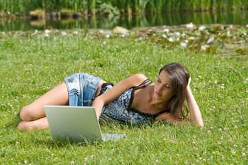 pretty girl working on laptop in a sunny day outdoor in the park