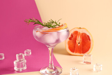 Purple gin and tonic served with ice cubes on color background