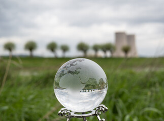 glass earth globe against nuclear power plant