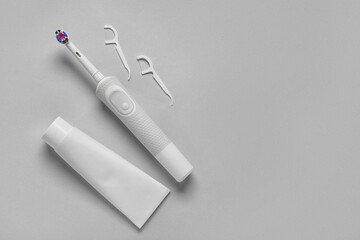 Electric toothbrush with paste and toothpicks on grey background